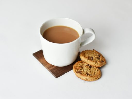 mug with coffee and two cookies on brown coaster