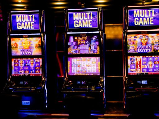 Three illuminated slot machines in a bustling casino at night.