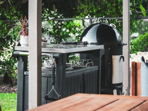 a grill outside with plants in the back