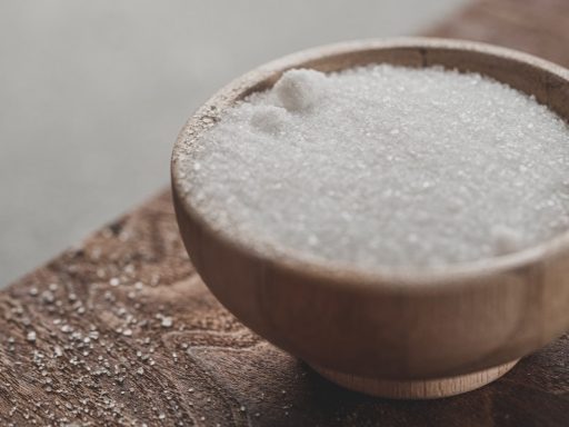 a wooden bowl filled with sugar on top of a wooden table