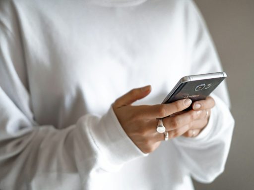 person in white long sleeve shirt holding black smartphone