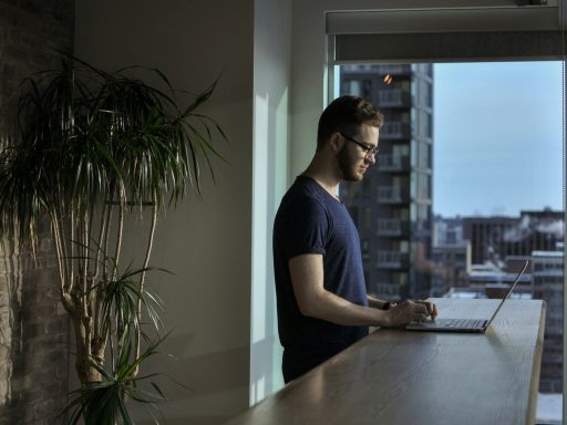 man standing beside table using laptop