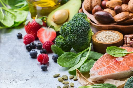 Een bord met diverse gezonde voeding waaronder noten, spinazie en volkoren brood als bronnen van magnesium, kalium en ijzer