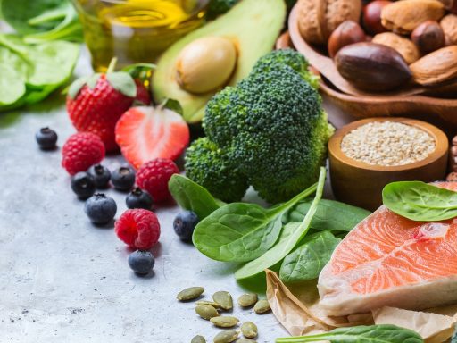 Een bord met diverse gezonde voeding waaronder noten, spinazie en volkoren brood als bronnen van magnesium, kalium en ijzer