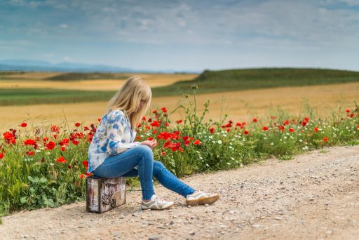 Persoon die vermoeid naast een half uitgepakte koffer zit na terugkomst van vakantie