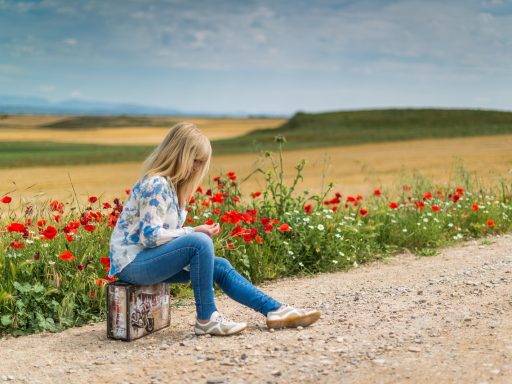 Persoon die vermoeid naast een half uitgepakte koffer zit na terugkomst van vakantie