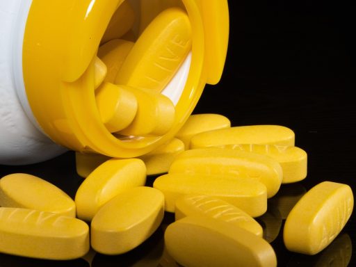 Een potje slaap gummies met melatonine op een nachtkastje naast een slapende persoon