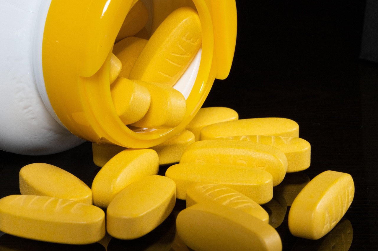 Een potje slaap gummies met melatonine op een nachtkastje naast een slapende persoon