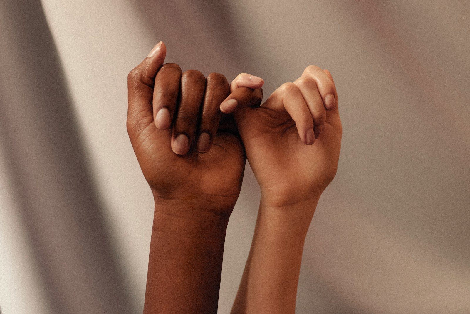 two hands with linked pinky fingers