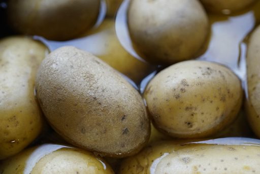 Diverse kaliumrijke voedingsmiddelen zoals bananen, spinazie, avocado en aardappelen op een houten tafel