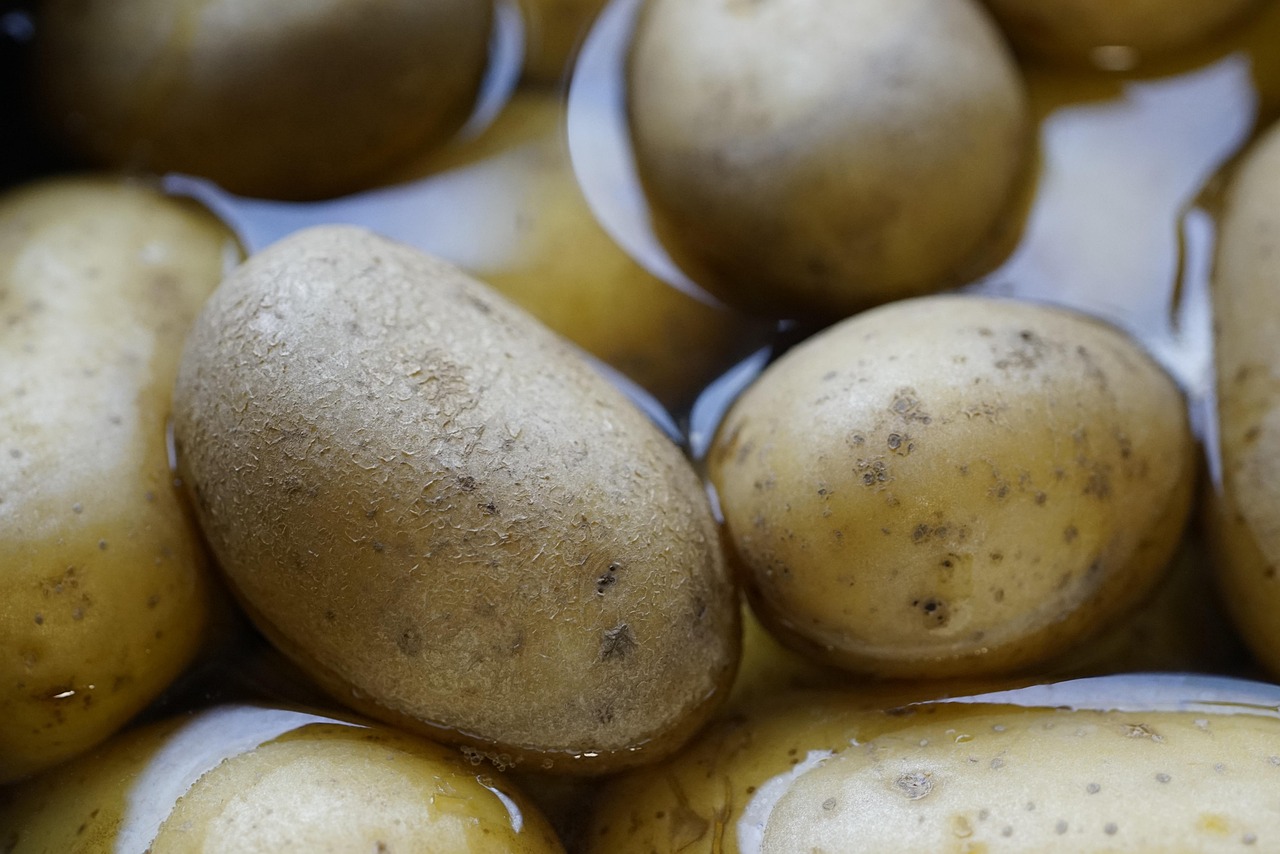 Diverse kaliumrijke voedingsmiddelen zoals bananen, spinazie, avocado en aardappelen op een houten tafel